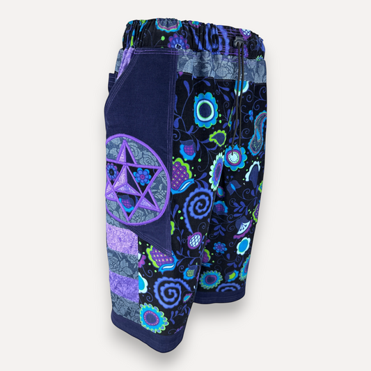 nowAwear shorts featuring a dark blue floral pattern, patchwork side pockets, and a purple star applique design.