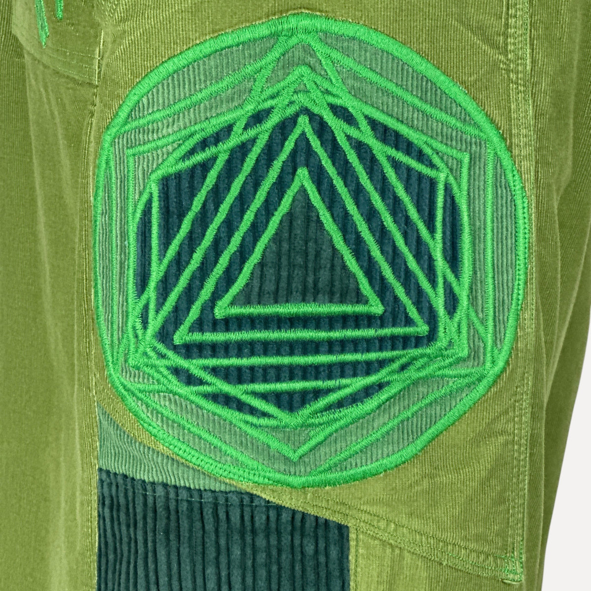 nowAwear medium green corduroy shorts featuring a large circular geometric embroidered patch with triangle patterns