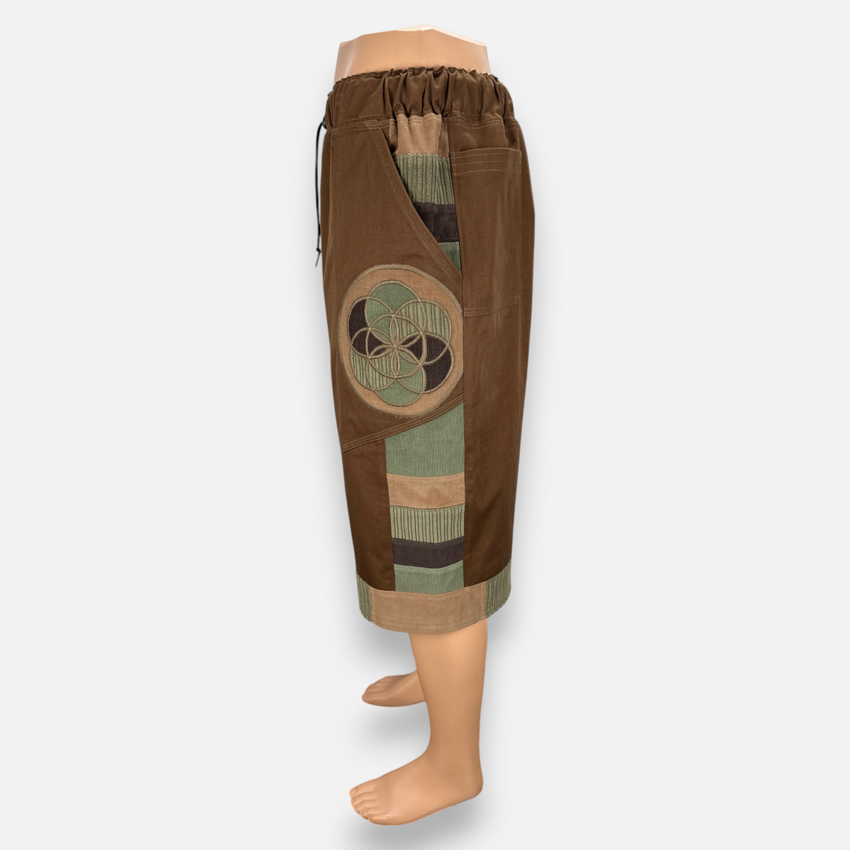 nowAwear brown medium twill shorts featuring a circular geometric patch, corduroy paneling, and an elastic waistband.