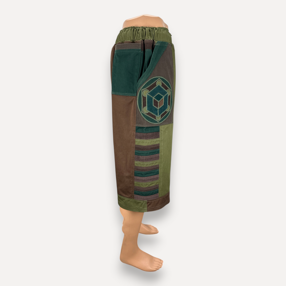 nowAwear medium brown and green patchwork shorts with geometric embroidery and elastic waistband on a mannequin