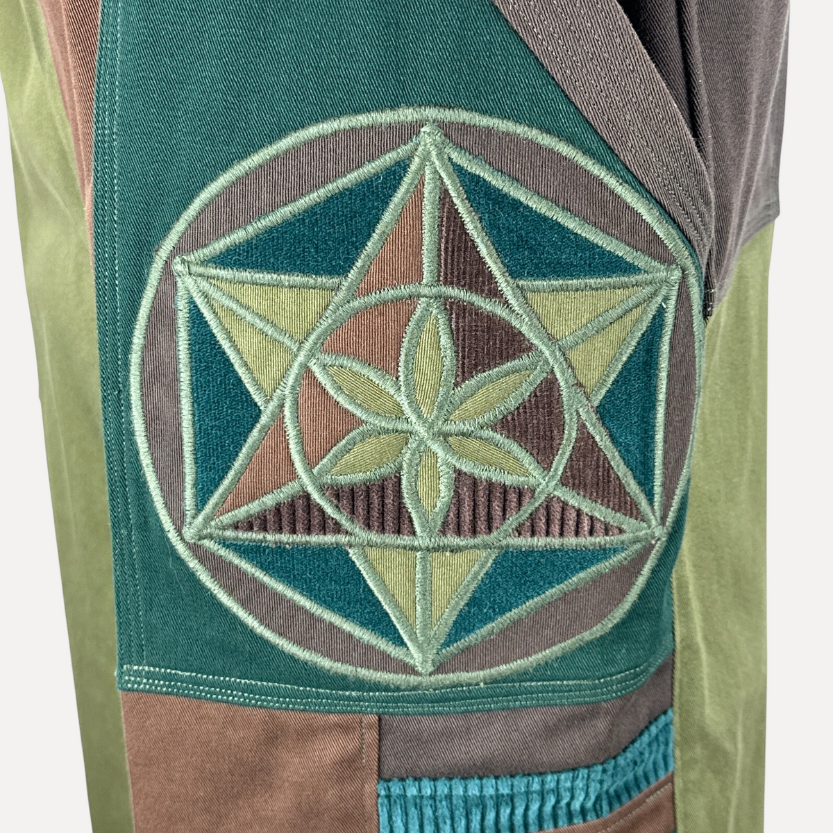 nowAwear medium brown and green shorts featuring a detailed embroidered sacred geometry flower of life patch