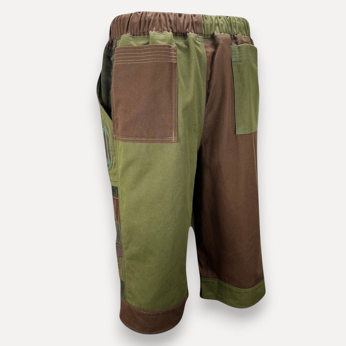 nowAwear shorts featuring a two-tone olive green and brown patchwork design with an elastic waistband and side pockets.