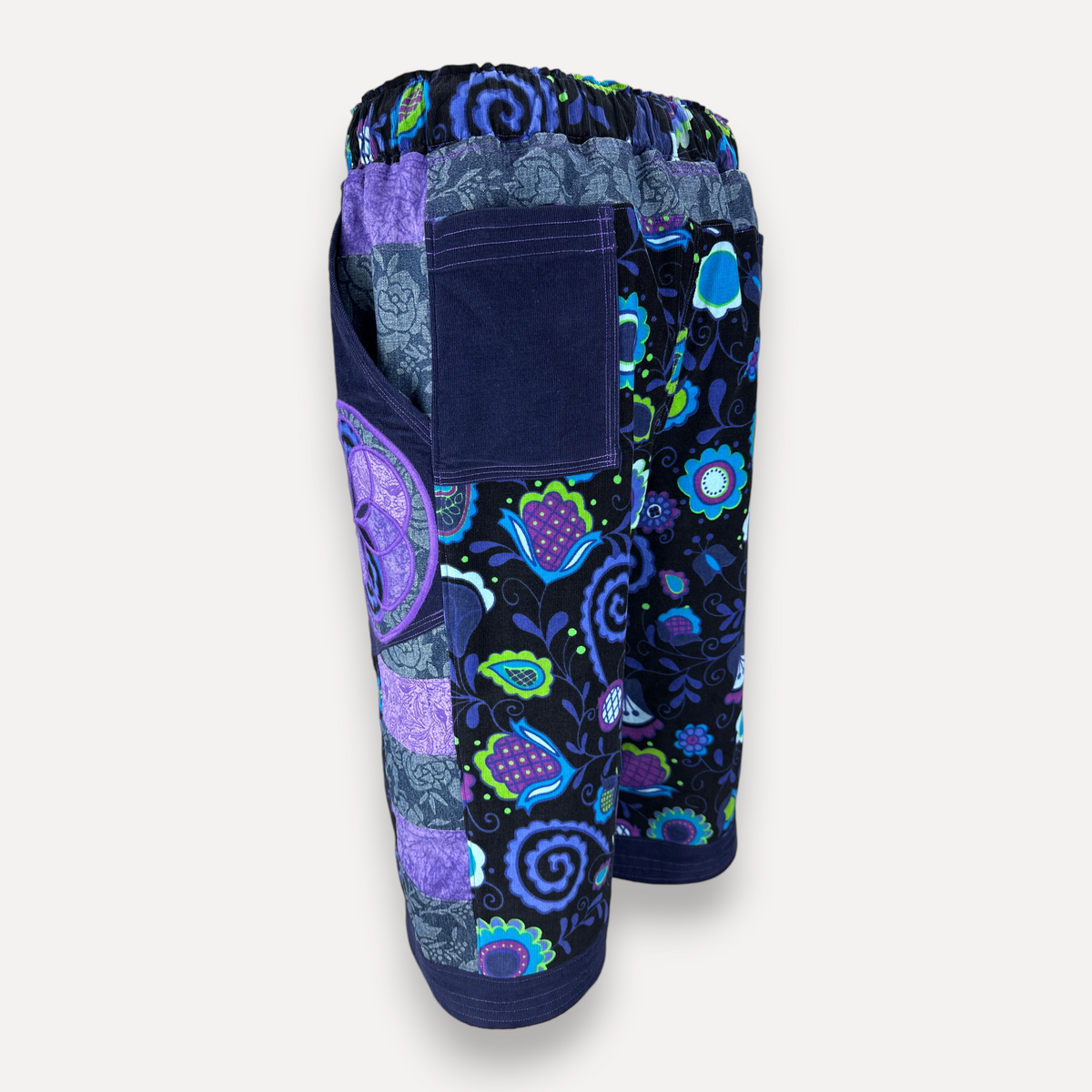 nowAwear patchwork shorts featuring vibrant floral and paisley patterns in purple, blue, and green with side pockets