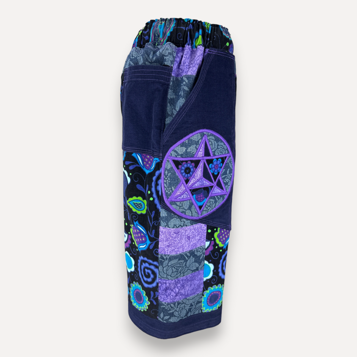 nowAwear shorts featuring a patchwork design with purple and blue floral patterns and a prominent star emblem pocket